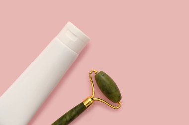 Cosmetic roller for the face, white container on a pink background.