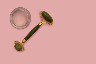 Cosmetic roller for the face, white container on a pink background.