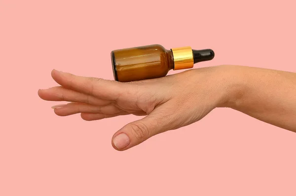 Hand holds a white container with cosmetic lotion. For hand care.