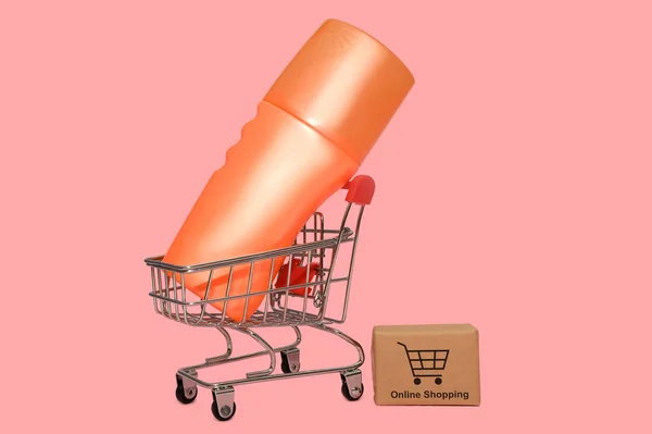 En una mini canasta de hierro. Envase naranja con crema. Compra y venta en línea. — Foto de Stock