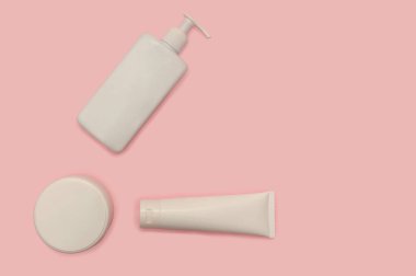 Beyaz plastik bir kapta cilt kremi ve losyon. Yakın plan. Pembe bir arka planda.