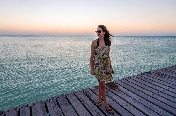 Ung kvinna som står på seaside brygga vid vackra solnedgången — Stockfoto
