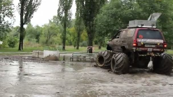 Grote bigfoot auto volledig in vuil draait rond modderpoel — Stockvideo