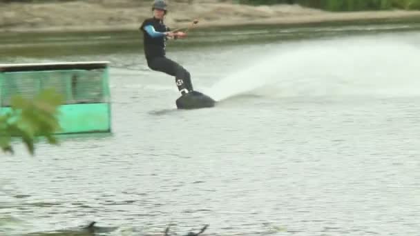 Profesionální wakeboarder skoky na trampolíně, přistane na vodě — Stock video