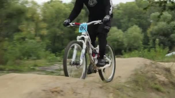 Racer monta bicicleta BMX en casco en el circuito de competición diurno — Vídeos de Stock
