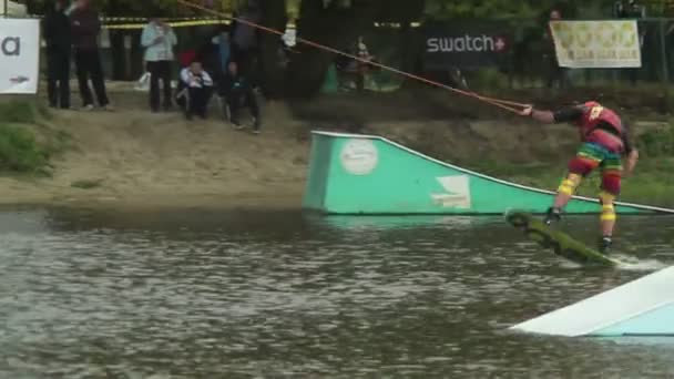 Uitvoeren van trucs mannelijke, wakeboarden wedstrijd, getrokken door kabel — Stockvideo