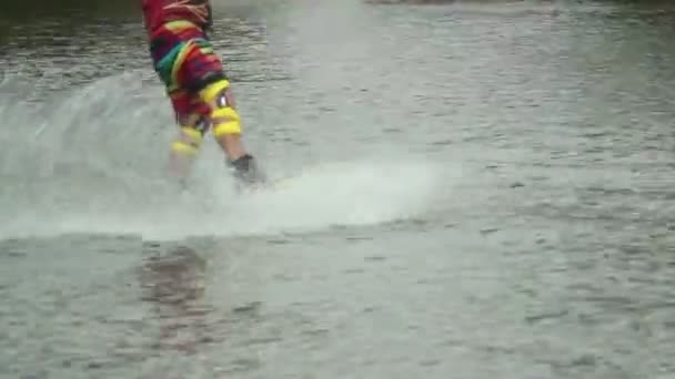 Wake-boarder in colorful sport suit rides water track splashes — Stock Video