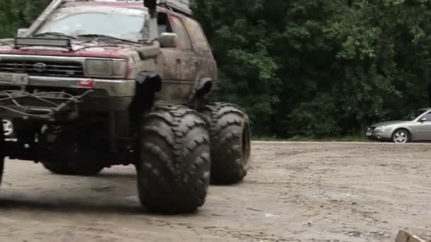 Large bigfoot driving away, wheels and glasses in dirt mud — Stok video