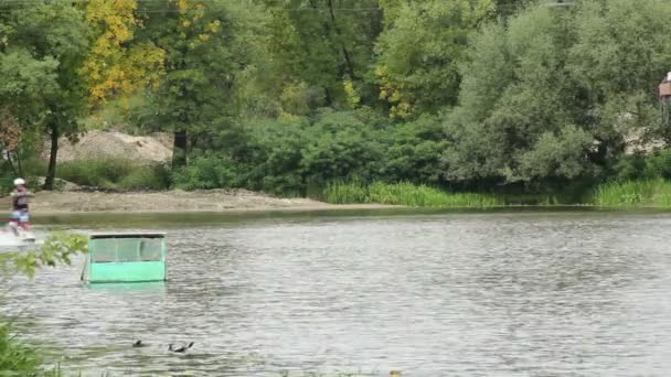 Wakeboarder parcourt la piste d'eau à bord suspendue au câble 