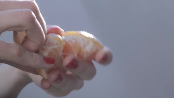 Händerna på ung kvinna skal orange frukt — Stockvideo
