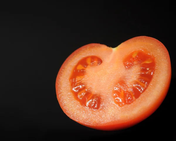 Meio tomate sobre um fundo preto — Fotografia de Stock