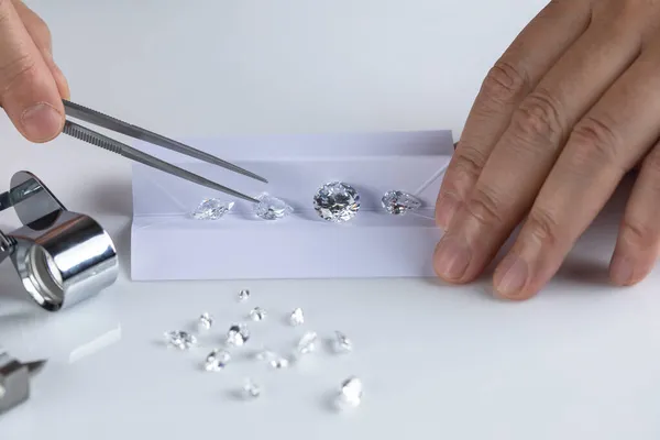 Close-up van diamantexperts hand op werkplaats voor de beoordeling van geslepen diamanten. — Stockfoto