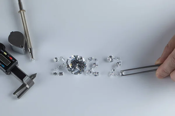 Процес викладання кількості 2022 з алмазів різних розмірів і форм за допомогою інструментів на робочому місці алмазного дилера. Концепція алмазного бізнесу 2022 . — стокове фото