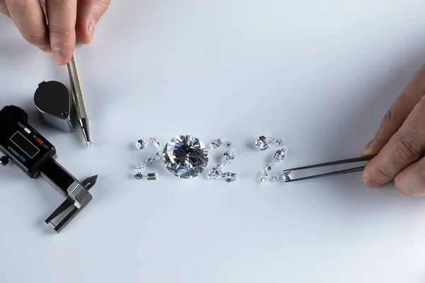 Proceso de trazar el número 2022 de diamantes de diferentes tamaños y formas utilizando herramientas en el lugar de trabajo del distribuidor de diamantes. Concepto de negocio del diamante 2022. — Foto de Stock