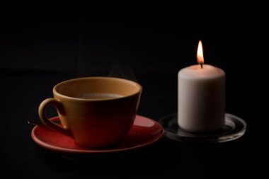 Sıcak dumanlı bir fincan çay ve mum. evdeki masada, elektrik kesintisi (fincana odaklan).