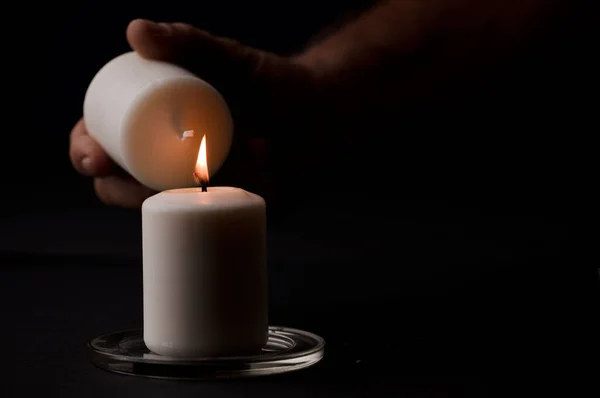 stock image burning candle with flame, man's hands lighting candle, black background. (focus on candle).