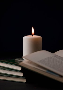 Ateşli mumlar, ve masada kitap okumak, siyah arka plan. (muma odaklan).