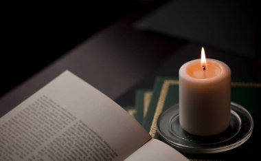 Ateşli mumlar, ve masada kitap okumak, siyah arka plan. (muma odaklan).