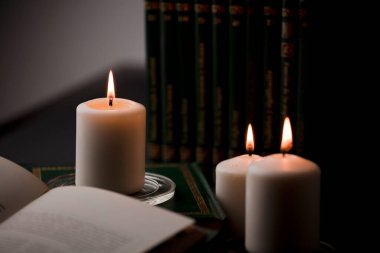 Ateşli mumlar, ve masada kitap okumak, siyah arka plan. (muma odaklan).