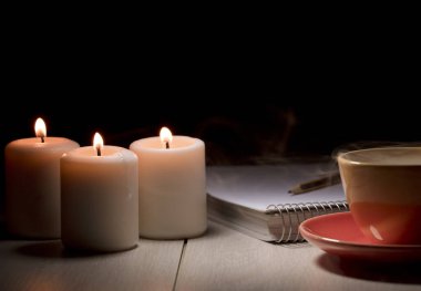 Üç mum, defter, kalem ve bir fincan sıcak çorba, elektrik kesintisi manzaralı..