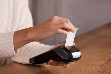 Faturayla işlem ödemesi yapan genç bir kadın ya da POS nakit terminalinin faturasını bir dükkanda, finansal konseptte kesiyor. Eline odaklan.