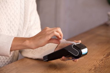 Faturayla ödeme yapan genç bir kadın ya da POS nakit terminalinin faturasını bir dükkanda, finansal dolandırıcılıkta kesiyor. Parmağına odaklan..