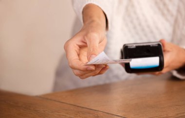 Faturayla işlem ödemesi yapan genç bir kadın ya da POS nakit terminalinin faturasını bir dükkanda, finansal konseptte kesiyor. Eline odaklan.