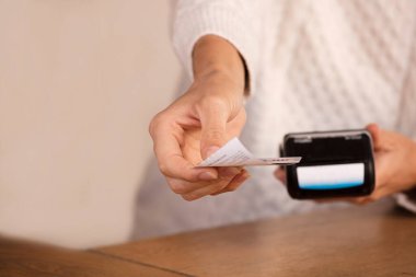 Faturayla işlem ödemesi yapan genç bir kadın ya da POS nakit terminalinin faturasını bir dükkanda, finansal konseptte kesiyor. Eline odaklan.