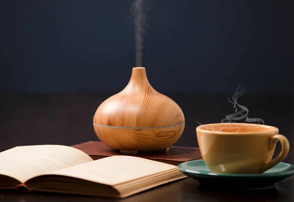 Relaxation at home with aromatherapy oil diffuser, yellow tea cup, open book. Aroma essence of health, wellness aromatherapy home aromatic tranquil therapy.