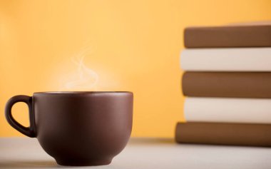 Kahverengi kahve ya da sıcak buharlı çay, masanın üstünde, kitaplarla.