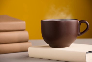 Kahverengi kahve ya da sıcak buharlı çay, masanın üstünde, kitaplarla.
