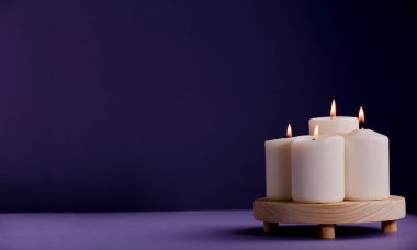 Tahtada alevi olan mumlar grubu ve menekşe arkaplan, metin için boşluk.