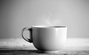Beyaz kahve fincanı, ahşap masada sıcak buhar dumanı, gri arka plan, beyaz ve siyah.
