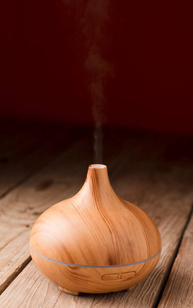 essential oil diffuser, wooden with graceful and smooth curves, red background