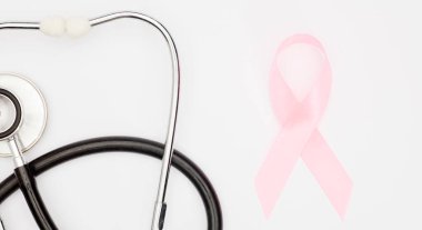 Pembe kanser kurdelesi, steteskop, beyaz arka plan, göğüs kanseri farkındalığının uluslararası sembolü ve kadınlar için moral desteği. İzole edilmiş arkaplan,