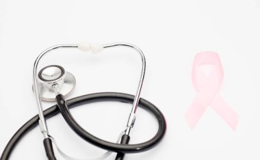 Pembe kanser kurdelesi, steteskop, beyaz arka plan, göğüs kanseri farkındalığının uluslararası sembolü ve kadınlar için moral desteği. İzole edilmiş arkaplan,