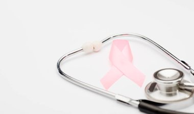 Pembe kanser kurdelesi, steteskop, beyaz arka plan, göğüs kanseri farkındalığının uluslararası sembolü ve kadınlar için moral desteği. İzole edilmiş arkaplan,