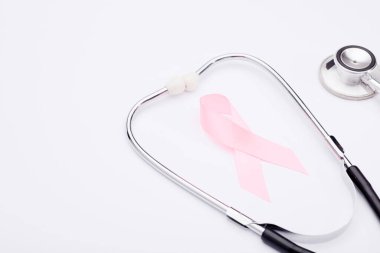 Pembe kanser kurdelesi, steteskop, beyaz arka plan, göğüs kanseri farkındalığının uluslararası sembolü ve kadınlar için moral desteği. İzole edilmiş arkaplan,