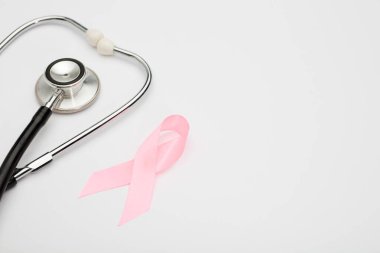 Pembe kanser kurdelesi, steteskop, beyaz arka plan, göğüs kanseri farkındalığının uluslararası sembolü ve kadınlar için moral desteği. İzole edilmiş arkaplan,