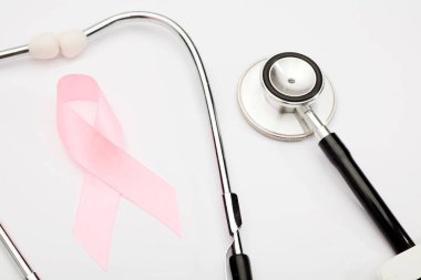 Pembe kanser kurdelesi, steteskop, beyaz arka plan, göğüs kanseri farkındalığının uluslararası sembolü ve kadınlar için moral desteği. İzole edilmiş arkaplan,