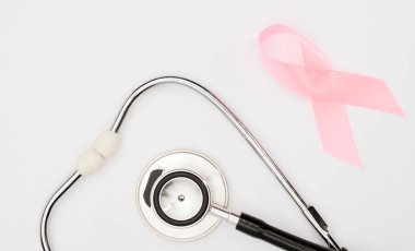 Pembe kanser kurdelesi, steteskop, beyaz arka plan, göğüs kanseri farkındalığının uluslararası sembolü ve kadınlar için moral desteği. İzole edilmiş arkaplan,