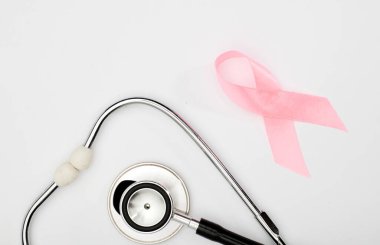 Pembe kanser kurdelesi, steteskop, beyaz arka plan, göğüs kanseri farkındalığının uluslararası sembolü ve kadınlar için moral desteği. İzole edilmiş arkaplan,