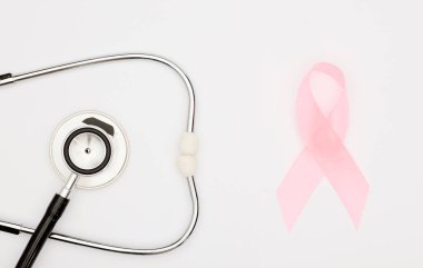 Pembe kanser kurdelesi, steteskop, beyaz arka plan, göğüs kanseri farkındalığının uluslararası sembolü ve kadınlar için moral desteği. İzole edilmiş arkaplan,