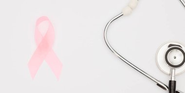 Pembe kanser kurdelesi, steteskop, beyaz arka plan, göğüs kanseri farkındalığının uluslararası sembolü ve kadınlar için moral desteği. İzole edilmiş arkaplan,