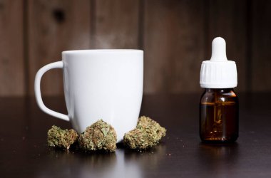 Marihuana tomurcukları yağ damlası dağıtıcısı, ve beyaz bardak, koyu ahşap arka plan