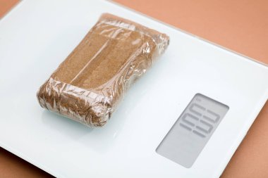 Ağırlık ölçeğinde paketlenmiş haşhaş tableti, bronz arkaplan
