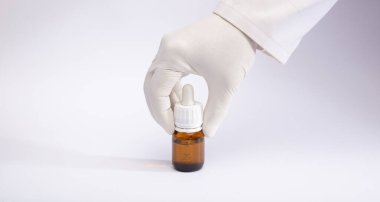 Teslimat kutusunda marihuana yağı eldivenli ellerde, beyaz arka planda.