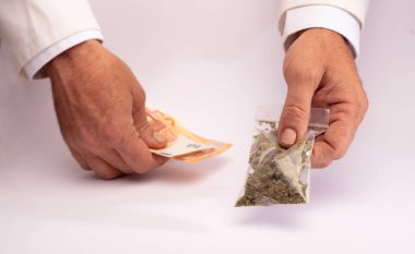Eczacı bir çanta dolusu tıbbi marihuana verdi ve parayı diğer eliyle beyaz bir tezgahın üzerinde aldı.