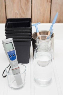 ev ekimi seti, ph sayacı, su şişesi, bitkiler için saksı, tarım aletleri, beyaz ve ahşap arka plan