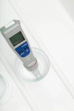Bir bardak suda pH ölçer ve beyaz arka planda bir şişe. İçme suyunun özelliklerinin ölçüsü. Suyun sertliği. İçme suyu kalite analizörü.